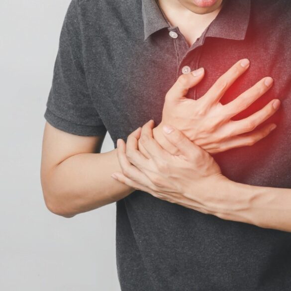 Homem segurando o peito com expressão de dor, indicando possível ataque cardíaco ou dor no coração.