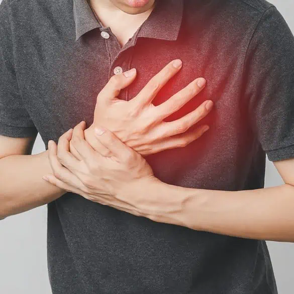 Homem segurando o peito com expressão de dor, indicando possível ataque cardíaco ou dor no coração.