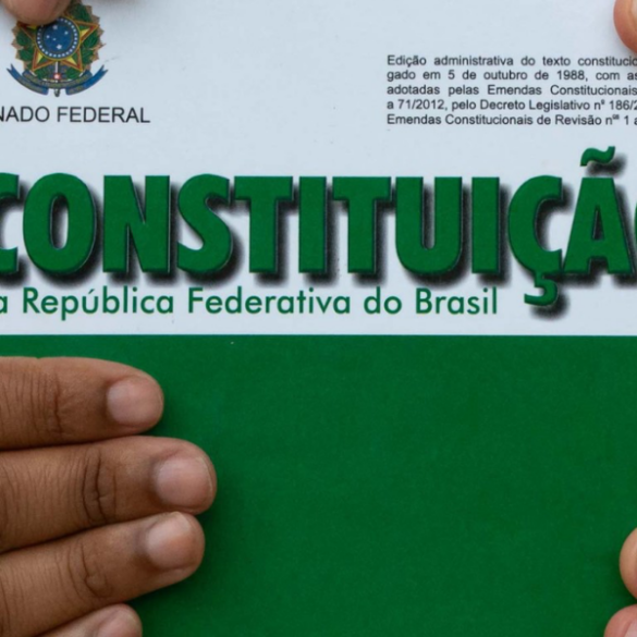 Pessoa segurando um exemplar da constituição da república federativa do brasil, edição do senado federal.