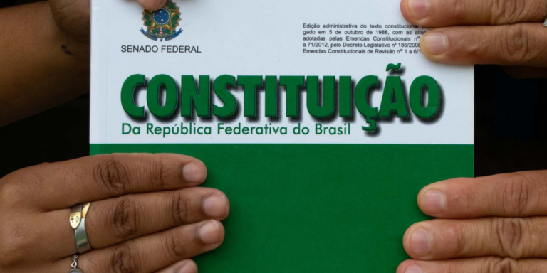 Pessoa segurando um exemplar da constituição da república federativa do brasil, edição do senado federal.