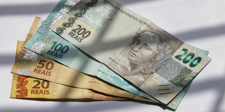 Notas de real brasileiro de 20, 50, 100 e 200 reais, moeda oficial do brasil, arranjadas sobre uma superfície branca.