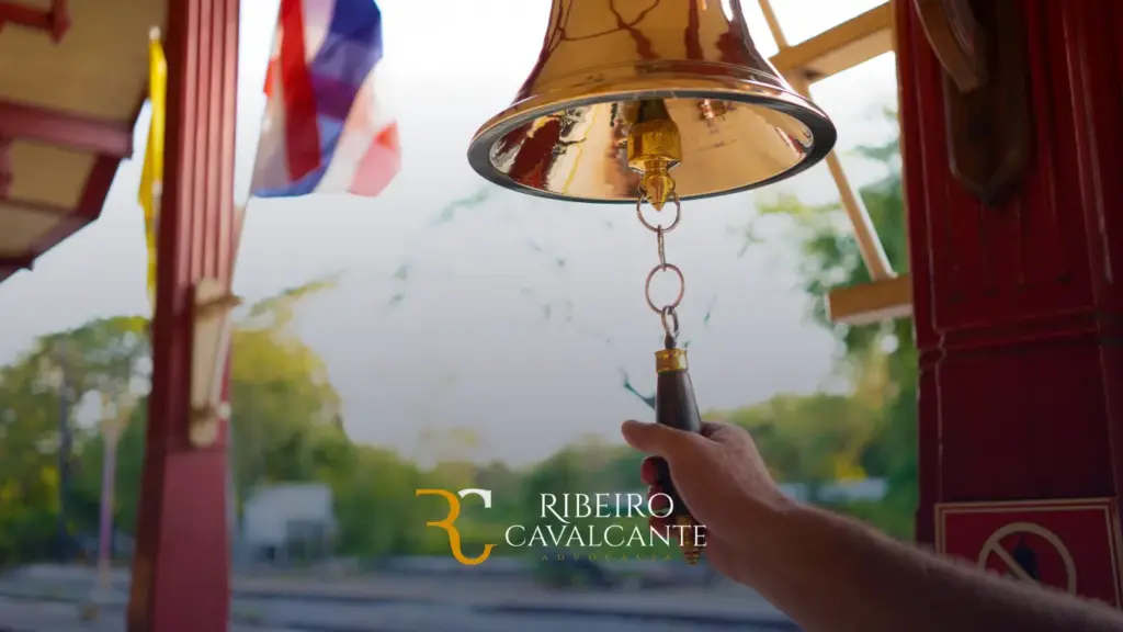 Mão acionando sino dourado em estação ferroviária